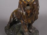 bronze statue of a lion on a rock on a gray background