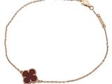 a gold bracelet with a red flower on a chain