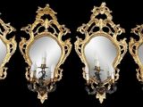 Trois miroirs aux cadres dorés sont accrochés à un mur noir.