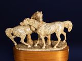 a statue of a group of horses on a wooden base