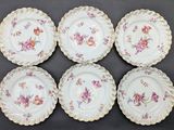 six plates with floral designs on them on a black surface