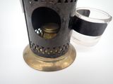a small metal candle holder with a glass on it