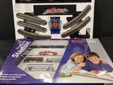 La boîte contient un circuit de train miniature avec deux enfants.