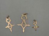 a group of three gold charms on a gray surface