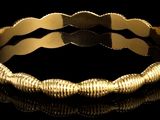 une image montrant un gros plan d'un bracelet en or posé sur une surface noire