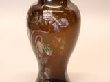 a brown vase with flowers on it sitting on a table