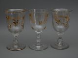 trois verres à pied ornés de motifs dorés, posés sur une table