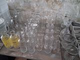 many empty glass bottles on a table with plates and cups