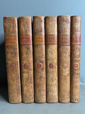 six vieux livres sont alignés les uns à côté des autres sur une étagère