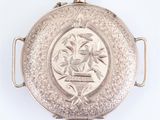 a silver pocket watch with a picture of a bird on it