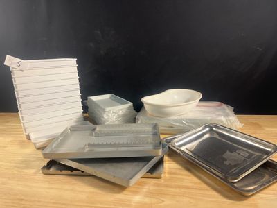 Plusieurs plateaux et plats sont posés sur une table, à côté d'une pile de papiers