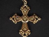 une croix dorée ornée d'un cœur, sur fond noir