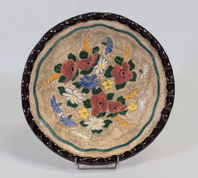 une image représentant une assiette décorative ornée de fleurs et de feuilles