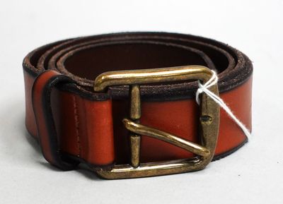 une ceinture marron avec une boucle en laiton sur un fond blanc