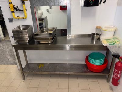 une table en acier inoxydable avec deux bols et un extincteur à l'arrière-plan