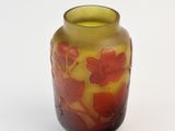 a yellow vase with red flowers on it on a white surface
