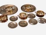 a lot of silver plates and bowls on the table