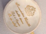 a white cup with gold writing on it sitting on a table
