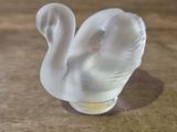 a glass swan figurine sitting on a wooden table