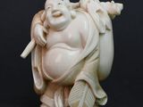 a white statue of a laughing buddha holding a stick