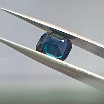 un diamant bleu maintenu par une paire de pinces