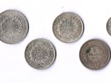 six types différents de pièces d'argent sur une surface blanche