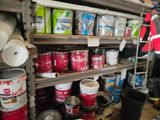 many buckets of paint on the shelves in the garage