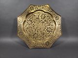 a gold plate with intricate designs on it on a gray background