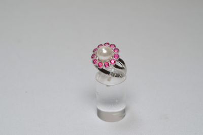 a close up of a ring with a pearl and pink stones