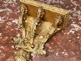 étagère plaquée or, ornée de trois têtes et d'une fleur, posée sur une table en marbre