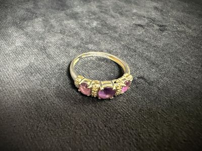 a close up of a gold ring with pink stones