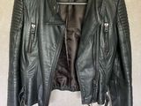 a black leather jacket hanging on a hanger on a wall