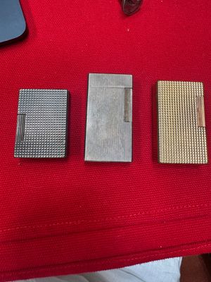 three lighters sitting on a red table with a laptop in the background