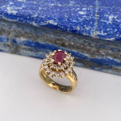 a close up of a gold ring with a ruby and diamond center