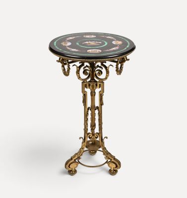 une petite table avec un plateau en marbre noir et des pieds en métal doré
