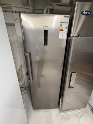 a silver refrigerator and a white refrigerator in a room