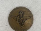 a bronze button with a bird on it on a white surface