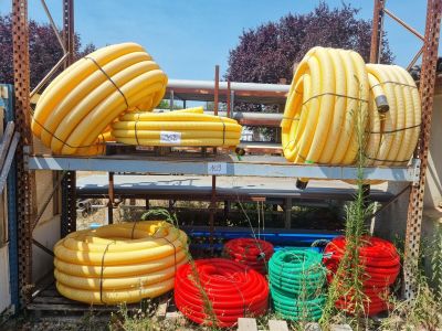 several yellow and red hoses are stacked on a metal rack