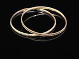 a pair of gold hoop earrings on a black surface