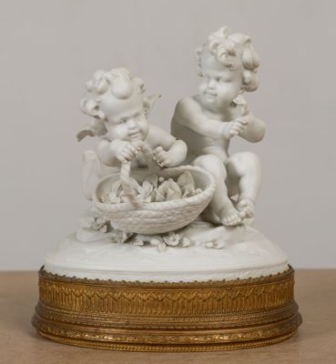 une statue blanche représentant deux chérensils, avec un panier de chérensils posé sur une table