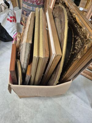 une boîte remplie de cadres posée par terre