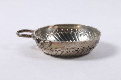 un plat ancien en argent, muni d'une poignée et orné d'un motif floral