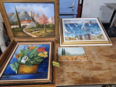 trois tableaux posés sur une table, avec un vase de fleurs