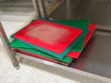 plusieurs tapis de découpe rouges et verts posés sur une étagère métallique
