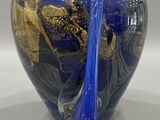 a blue glass vase with a gold design on it