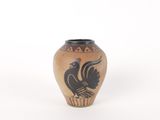 un petit vase avec un oiseau sur une surface blanche