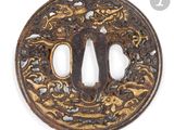 a close up of a round iron tsuba with a design on it