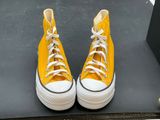 yellow converses with white laces are on display in a display case