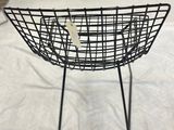 a wire basket on a stand on a white sheet