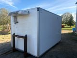a small white refrigerator sitting in the middle of a field